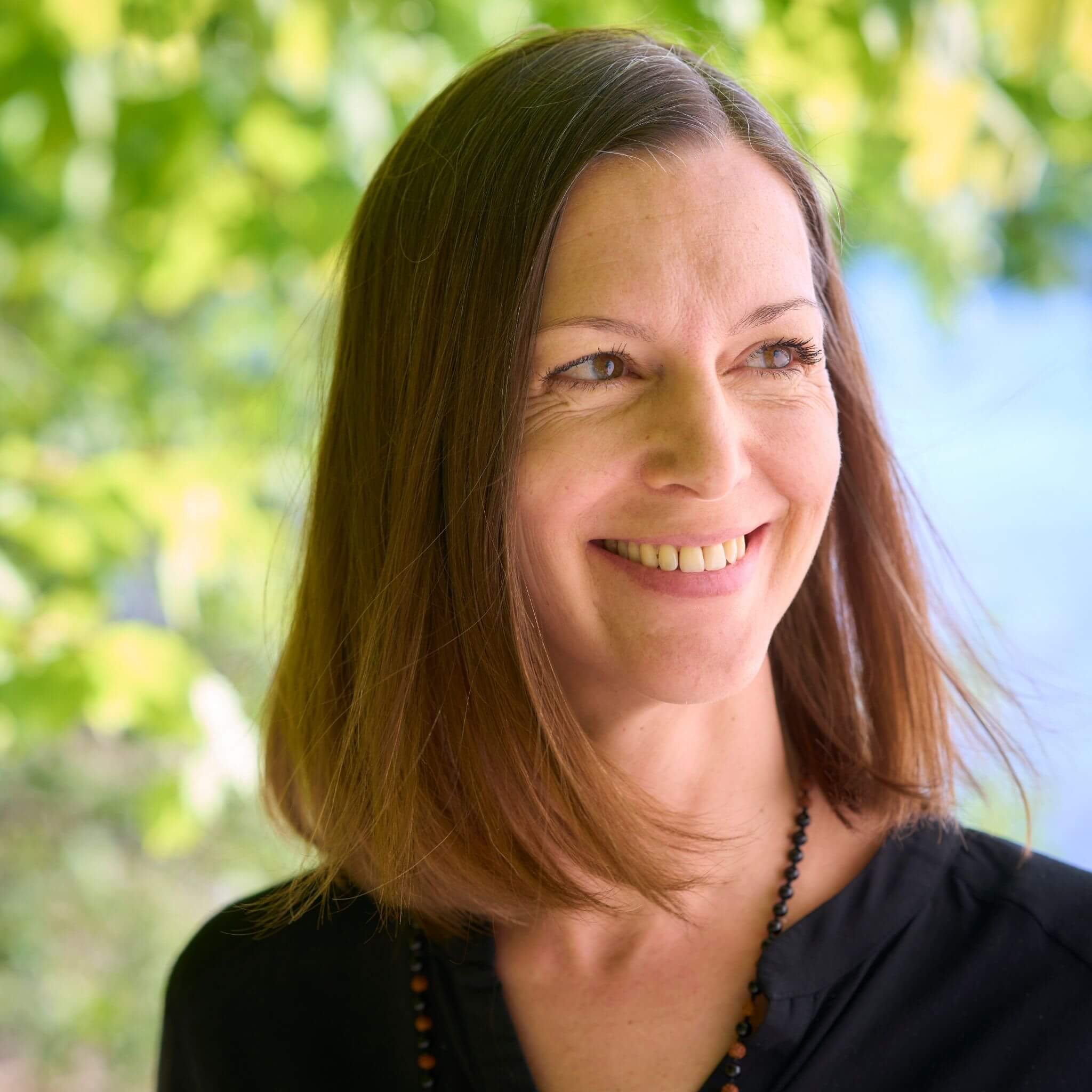 Über mich - Dr. Birgit Greiner lächelt im Grünen – Porträt für die über mich Seite über Human Design Coaching