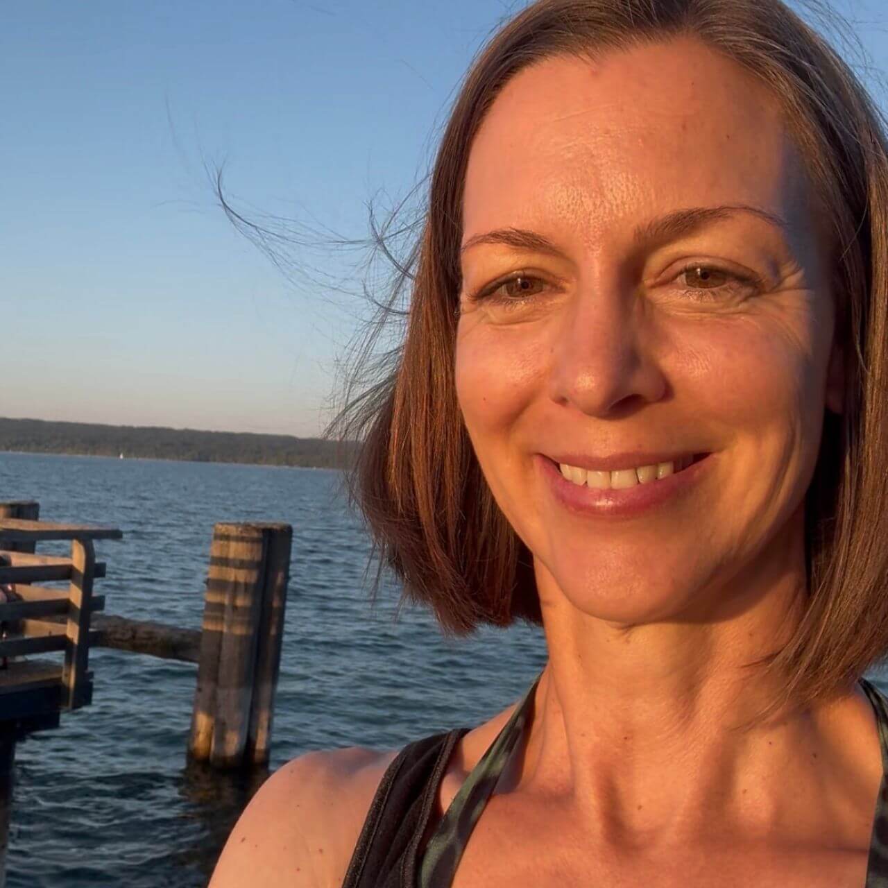 Human Design beobachten – Dr. Birgit Greiner an einer Seeanlegestelle im Abendlicht