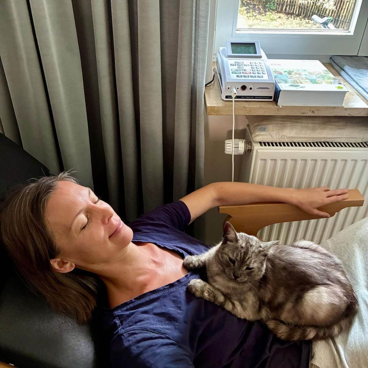 Bioresonanz Erfahrung – Dr. Birgit Greiner entspannt während einer Anwendung, die Katze liegt auf ihrer Brust
